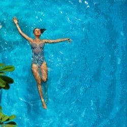 Woman In Pool Water. Beautiful Happy Girl With Sexy Fit Body Relaxing, Floating In Swimming Pool.
