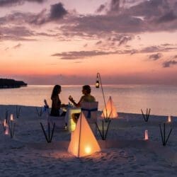 Couple is having a private event dinner on a tropical beach during sunset time prepared by Private Maui Chef.