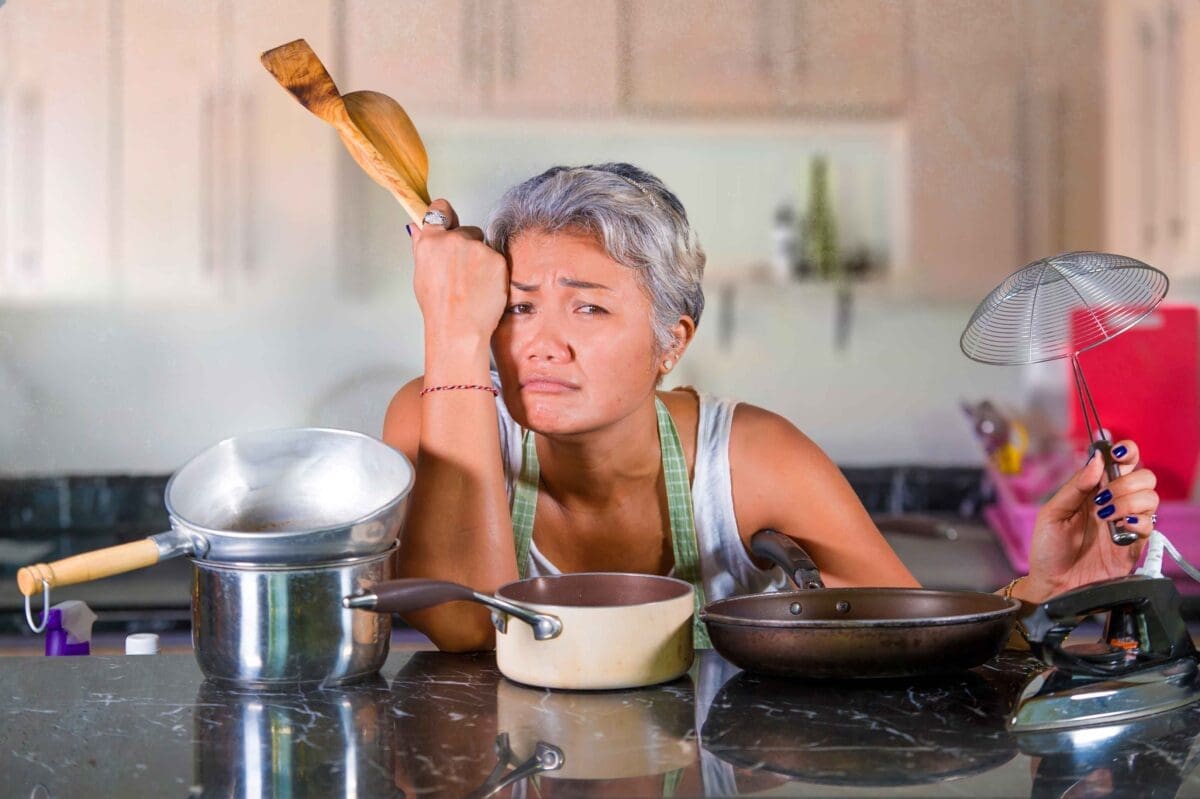 A woman on vacation stressed out and overwhelmed at having to prepare food on vacation.
