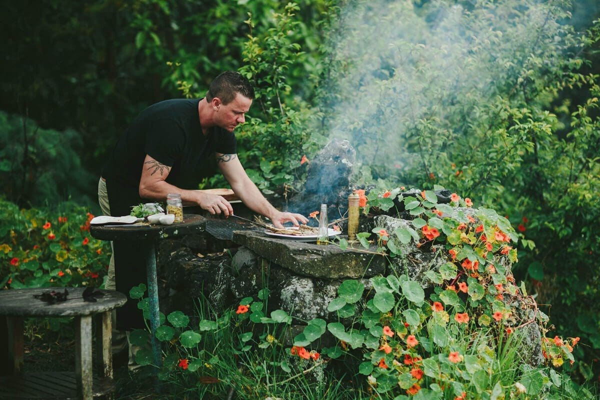 Chef Brian Etheredge of Private Maui Chef cooking outside on a stacked rock grill in the garden