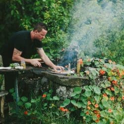 Chef Brian Etheredge of Private Maui Chef cooking outside on a stacked rock grill in the garden